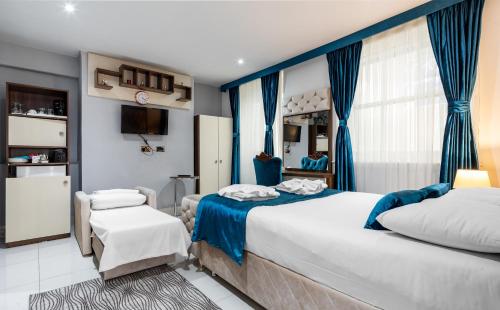 伦敦Vilenza Hotel的一间卧室配有两张带蓝色窗帘的床和电视。