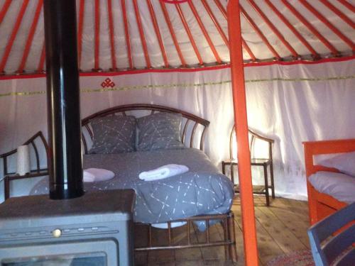 Saint-Léger-sur-DheuneYourte Mongole的蒙古包内一间卧室配有一张床铺,蒙古包配有炉灶