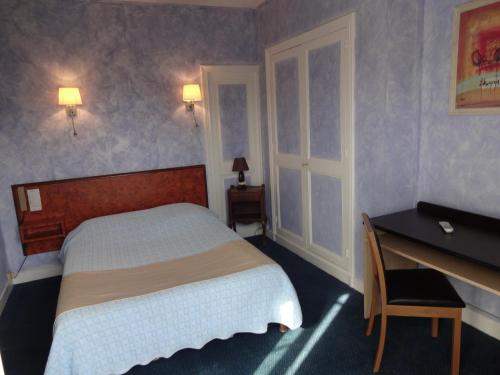 卡布尔Hôtel La Champagne Ardenne Cabourg的卧室配有1张床、1张书桌和1张桌子及椅子