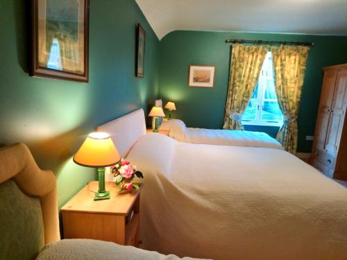 新罗斯Kilmokea Coach House的一间卧室配有两张床和一张带台灯的桌子