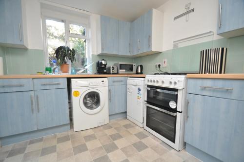 伦敦Large Garden flat in the heart of Islington的厨房配有蓝色橱柜和洗衣机。