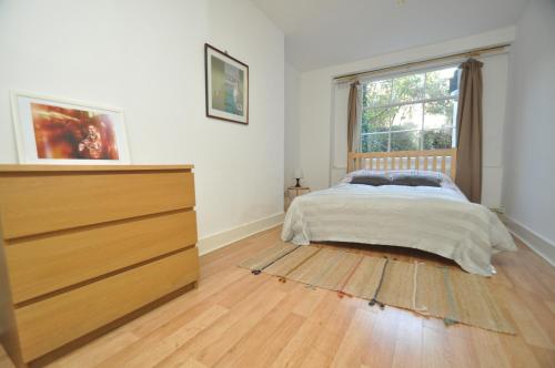 伦敦Large Garden flat in the heart of Islington的一间卧室配有一张床、一个梳妆台和一扇窗户。