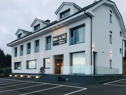 巴雷罗斯Rías Altas - Hotel Restaurante的一座大型白色建筑,设有停车场