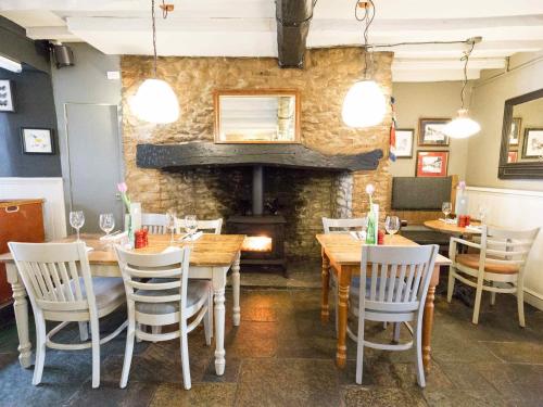 比斯特The Plough Bicester的一间带桌椅和壁炉的餐厅