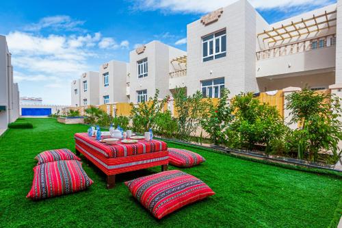 Al RuwisAl Asala Resort的草坪上配有桌子和四个枕头