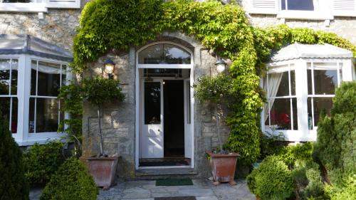 阿克斯明斯特Kerrington House的一座常春藤环绕着门口的石头房子