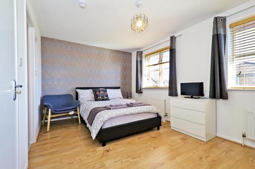 伦敦Harlinger Lodge Annexe的一间卧室配有一张床、一把椅子和电视