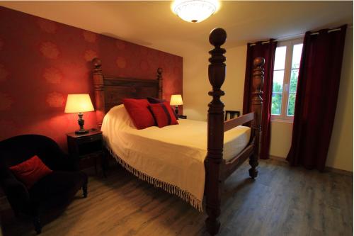 圣加蒂安代布瓦帕格力旅馆的一间卧室设有一张带红色墙壁的大床