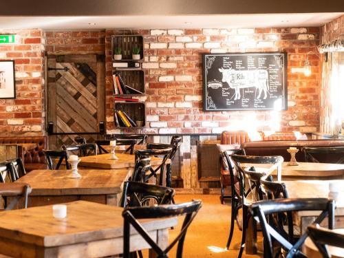 索厄比布里奇The Lion Pub & Grill的餐厅设有木桌和椅子,拥有砖墙