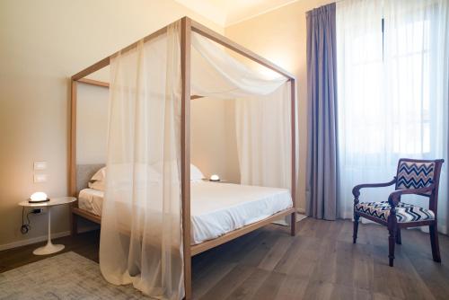 科森扎Dimora de Matera Luxury Suites的一间卧室配有一张天蓬床和一把椅子