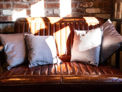 索厄比布里奇The Lion Pub & Grill的棕色皮沙发,配有四个枕头