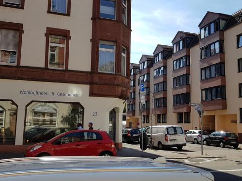 萨尔布吕肯瑙维瑟公寓式酒店的一辆红色的汽车停在城市街道上,街道上有许多建筑