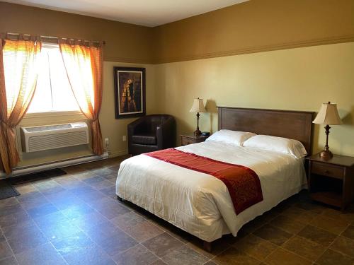 Plessisville莫泰乐法尔酒店的卧室配有床、椅子和窗户。