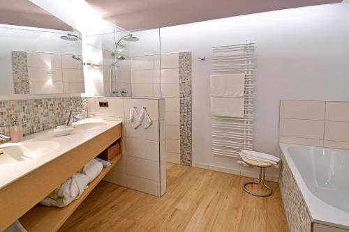 马尔克泰登费尔德Hotel & Weinhaus Anker的浴室配有2个盥洗盆、浴缸和淋浴。