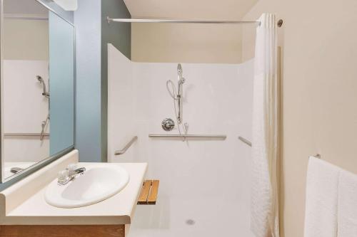 康瑟尔布拉夫斯WoodSpring Suites Council Bluffs的白色的浴室设有水槽和淋浴。