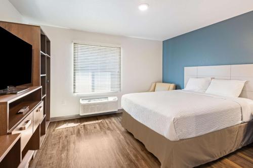达文波特WoodSpring Suites Davenport Quad Cities的一间卧室配有一张床和一台平面电视