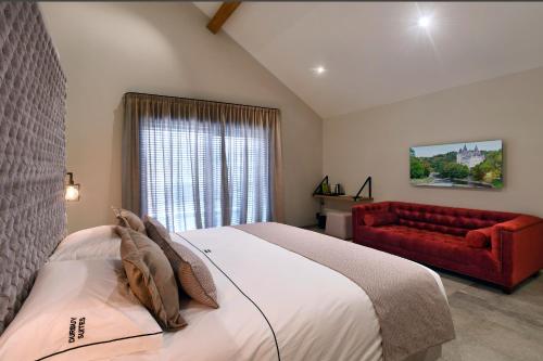 杜柏DURBUY SUITES的一间卧室配有一张床和一张红色的沙发