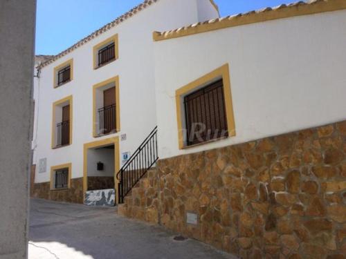 卡斯特里尔Alojamiento Rural El Chorrillo的白色的建筑,在街道旁有石墙