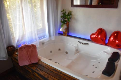 圣弗朗西斯科-迪保拉Pousada Recanto Vale da Serra Chales的浴缸上方有红色的心脏
