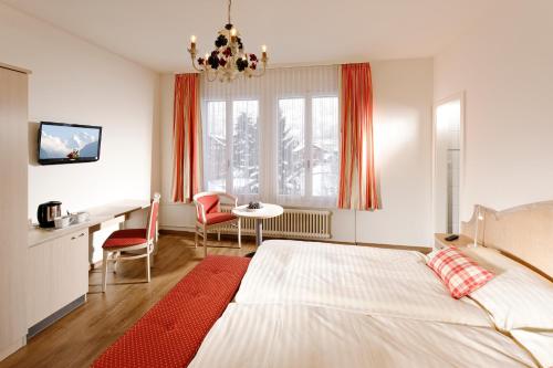 因特拉肯美地酒店的卧室配有一张床和一张桌子及椅子