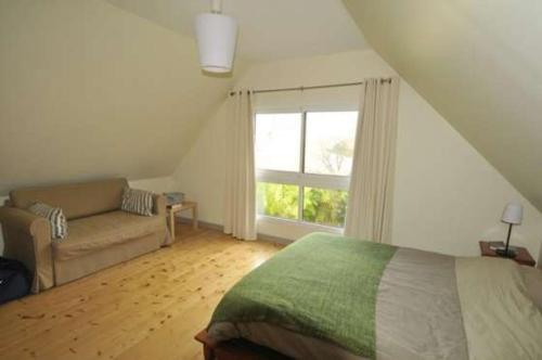 Locquénolé恩连珠杜丝花园度假屋的一间卧室配有一张床、一张沙发和一个窗口