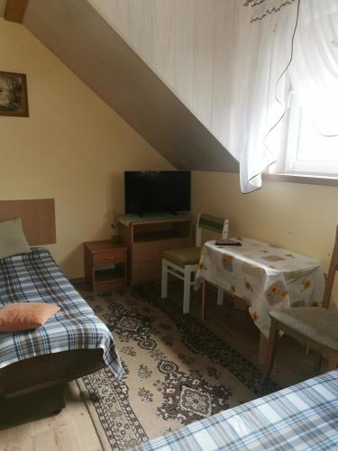 姆拉哥沃Czerwonki Apartament的客房设有两张床、一张桌子和电视。