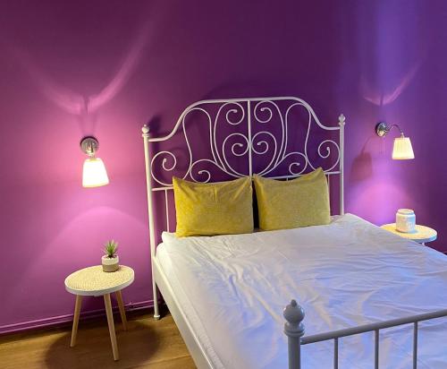 布拉索夫Drumul Poienii Apartment的紫色卧室配有一张床和两张桌子