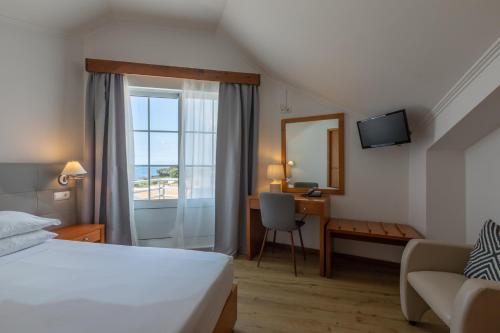 Rosário-Lagoa阿坎约酒店的配有一张床、一张书桌和一扇窗户的酒店客房