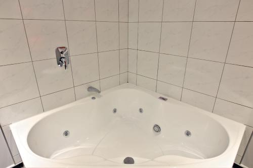 奥玛鲁奥玛鲁汽车旅馆的浴室设有白色浴缸,浴室设有瓷砖墙