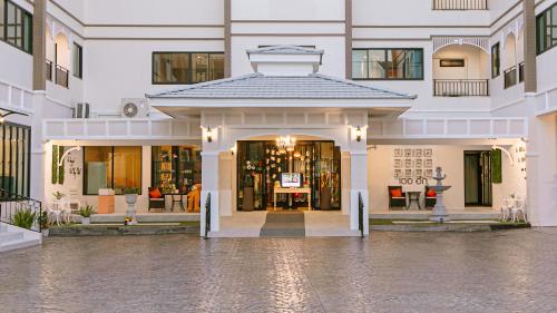 清莱德哈哥公寓酒店 的一座白色的大建筑,设有商店入口