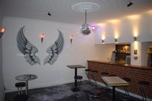 KalbeHotel Ratsstuben Kalbe的酒吧,墙上有两只翅膀,有凳子