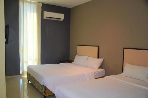 关丹Senrose Hotel Kuantan的一间卧室设有两张带白色床单的床和窗户。