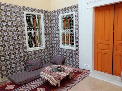 马赫迪耶Dar EL Hamra Maison Typique的一间设有桌子、两个窗户和一扇门的房间
