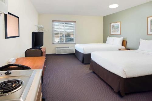 巴吞鲁日WoodSpring Suites Baton Rouge Airline Highway的酒店客房设有两张床和炉灶。