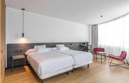 卢戈Hotel Forum Ceao的卧室配有白色大床和粉红色椅子