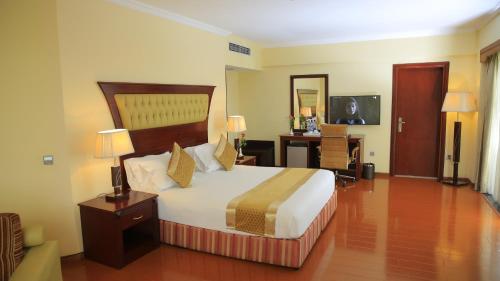 亚的斯亚贝巴Inter Luxury Hotel的酒店客房设有一张大床和一张书桌。