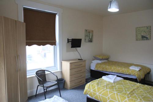 利物浦Clifton arms的一间卧室设有两张床、一把椅子和一个窗户。