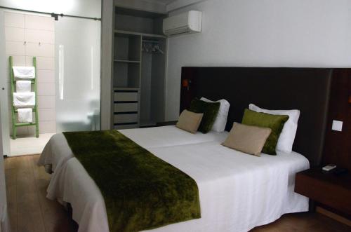 费雷拉杜阿连特茹雷塔托梅莫里亚卡萨德坎波酒店的一间卧室配有一张带绿毯的大床