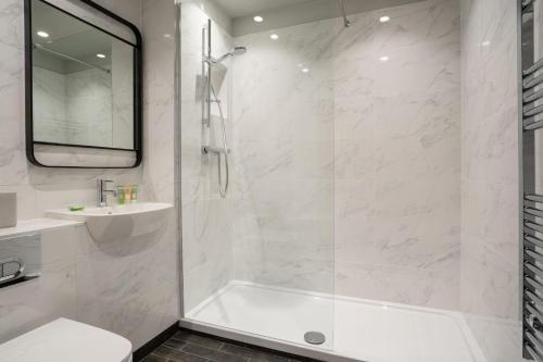 卡斯尔韦伦Hillyard House Hotel的带淋浴和盥洗盆的白色浴室