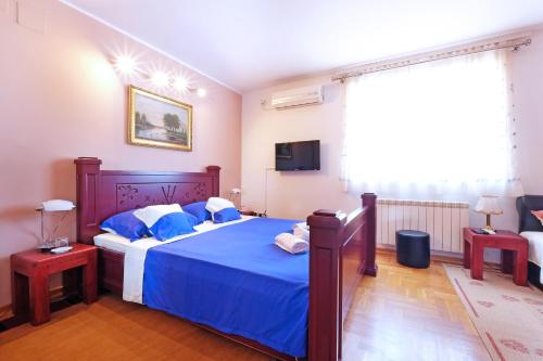 贝尔格莱德Villa Tower Gardos的一间卧室配有一张带蓝色床单的床和电视。
