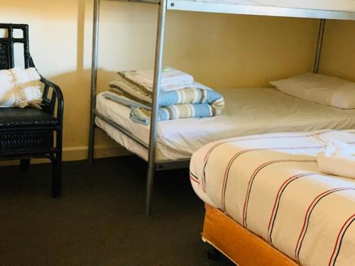 KootingalKootingal Hotel的一间卧室配有两张双层床和椅子