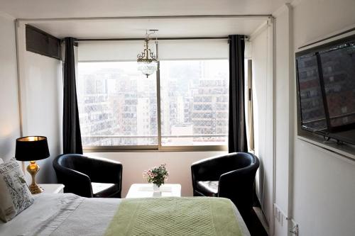 圣地亚哥Vip Home的一间卧室配有两把椅子、一张床和窗户