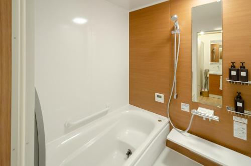 函馆箱館宿 観月-Mizuki-伝統的建築物の宿-最大8名宿泊可能的一间带大型白色浴缸和镜子的浴室