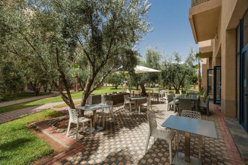 马拉喀什瓦佐公寓酒店 的庭院配有桌椅和树木