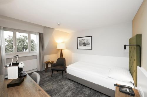 楚格络温西酒店的酒店客房配有一张床、一张桌子和一把椅子。