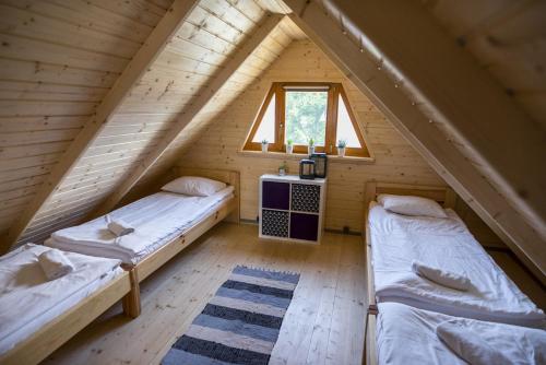 比斯库佩茨Dadaj Summer Camp - całoroczne domki Rukławki的木制阁楼间设有两张床,配有窗户
