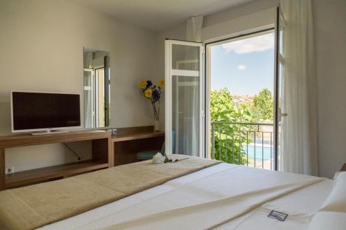 阿卡斯Pradaria Asador & Alojamiento的一间卧室设有一张带电视的床和一个阳台。