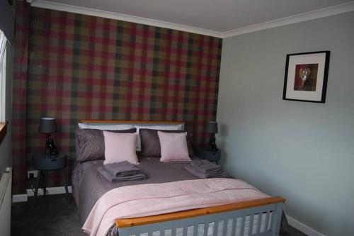 阿伯福伊尔Creag Mhor Self Catering Holiday Apartment的一间卧室配有带粉红色枕头的床