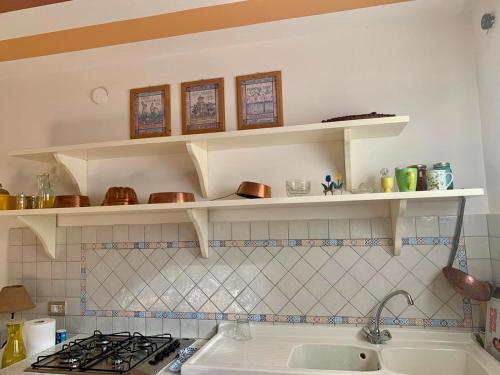 SindiaCasa Caterina in centro的厨房配有水槽上方的白色架子