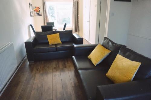 坎特伯雷The Harvest 2的客厅配有2张黑色沙发和黄色枕头